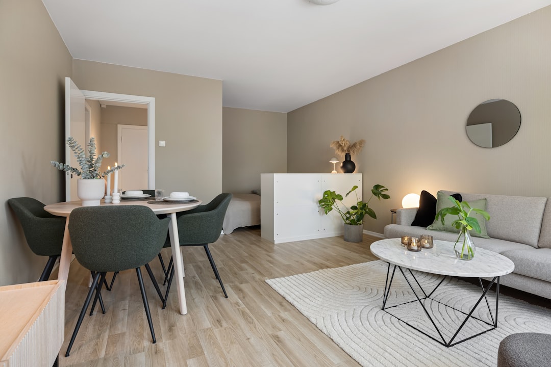 Modern minimalist living room and dining area with neutral tones, wooden flooring, and green indoor plants, creating a cozy and stylish home interior design.